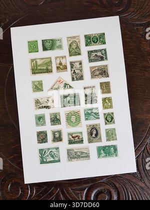 Une feuille de timbres-poste verts vintage du monde entier sur une table en chêne sculpté. Banque D'Images
