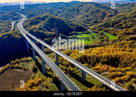 Vue aérienne de l'autoroute Egnatia surélevée au-dessus de la forêt d'automne dans le nord de la Grèce, montrant les infrastructures se mélangeant avec la nature. Banque D'Images