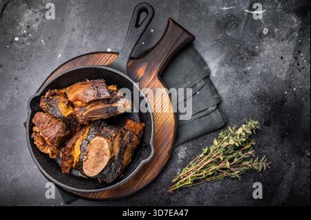 De courtes côtes de bœuf tendres dans une poêle, assaisonnées d'herbes et d'épices. Parfait pour les blogs culinaires ou les menus de restaurant qui se concentrent sur la viande copieux et savoureux d Banque D'Images
