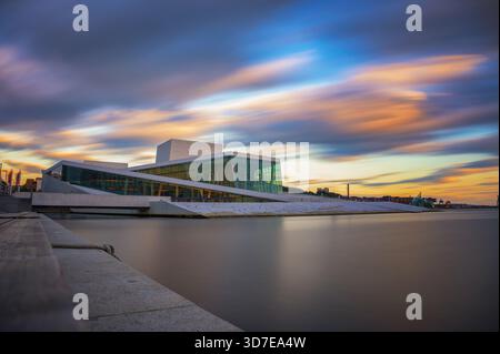 Oslo Opera House au coucher du soleil avec des eaux calmes du fjord et un ciel coloré, Norvège. Banque D'Images