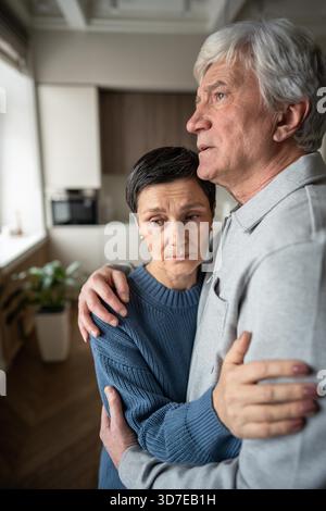 Femme senior dans le mari embrasser réconfortant l'humeur triste réfléchie. Soutien conjugal dans les difficultés, empathie de la famille aînée, amour des soins aux personnes âgées, problèmes de santé, partenaire consolant apaisant, vieillir les liens || modèle libéré Banque D'Images