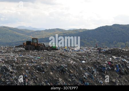 Bulldozer travaillant sur une décharge municipale à Subcarpathia, Pologne, entouré de déchets mélangés sur un site d'élimination actif. Banque D'Images