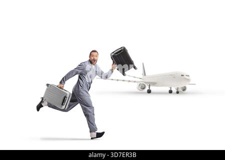 Homme excité en pyjama courant avec des valises pour attraper des vacances en avion isolé sur fond blanc Banque D'Images