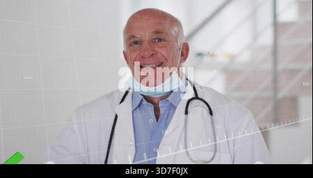 Médecin senior debout dans le couloir de l'hôpital portant une blouse de laboratoire, avec stéthoscope, masque abaissé, HUD Banque D'Images