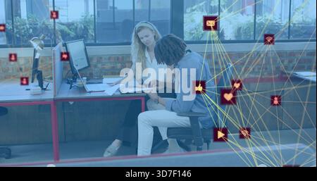 Examen de deux collègues penchés vers l'avant pointant vers des documents sur le bureau dans le bureau, superposition de réseau Banque D'Images