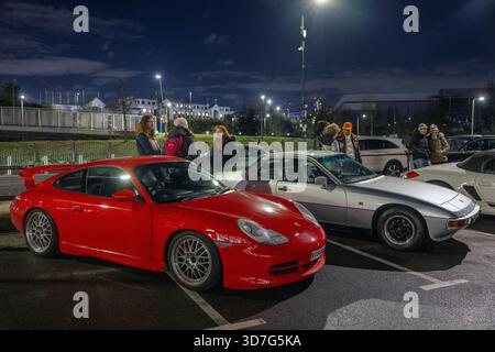Divers modèles Porsche, dont une 911 classique et une 944, sont garés devant l'emblématique Ace Cafe London lors d'un événement « Porsche Night » très animé. Banque D'Images
