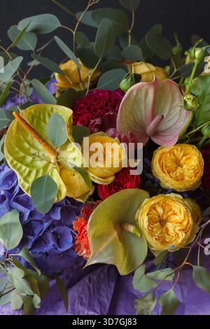 Un bouquet luxueux avec des fleurs vertes d'Anthurium andraeanum, des fleurs de Rosa jaunes, une Hydrangea macrophylla violette profonde et un feuillage d'eucalyptus Banque D'Images