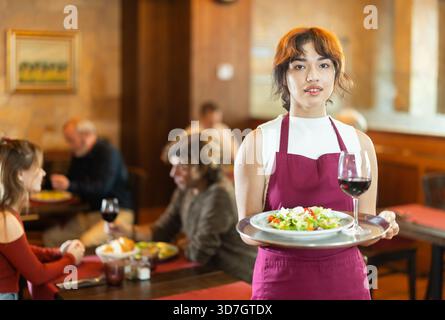 Jeune serveuse féminine avec commande sur plateau dans le restaurant Banque D'Images