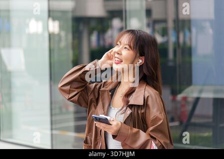 Femme asiatique souriante appréciant le style de vie du shopping, tenant des sacs près du centre commercial de la ville, habillé à la mode Banque D'Images