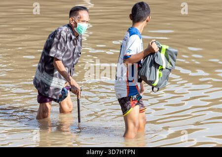 BANGKOK, THAÏLANDE, nov 09 2025, les gens pataugent prudemment dans une rue inondée Banque D'Images