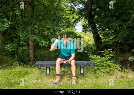 Homme mature excité avec des poissons dans l'air regardant smartphone, succes gagné de l'argent ou du travail ou du sport gagner Banque D'Images