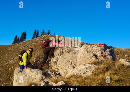 Deux randonneurs gravissent un terrain rocheux dans une zone montagneuse ensoleillée pendant une journée claire au début de l'automne Banque D'Images