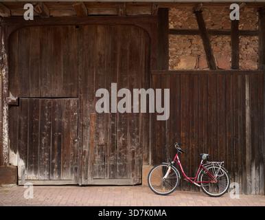Une bicyclette pour dames appuyée contre une vieille porte de grange dans les Alpes bavaroises Banque D'Images