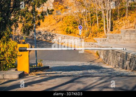 Une barrière de circulation jaune et blanche se trouve sur une route. La porte est vide Banque D'Images