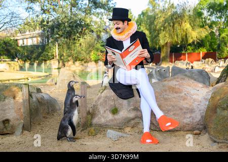 Londres, Royaume-Uni. 26 novembre 2025. Le comédien Garry Starr accueille le premier club de lecture de pingouins au monde au zoo de Londres. Il est accompagné par Humboldt Penguins Kermit, Marley, Lorde et ses amis pour une lecture du Frankenstein de Mary Shelley. Son spectacle « Garry Starr : Classic Penguins » est actuellement en cours au Arts Theatre et sera transféré au Garrick Theatre le 1er février 2026. Le crédit photo devrait se lire comme suit : Matt Crossick/Empics/Alamy Live News Banque D'Images