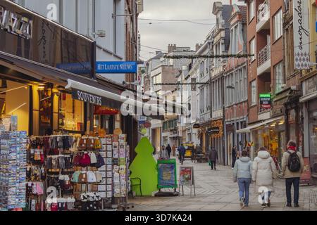 Beaux bâtiments et boutiques de souvenirs le long d'une rue commerçante piétonne dans le centre-ville de Gand Belgique. Photo prise par un jour nuageux en Flandre Banque D'Images