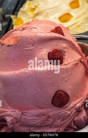 Gelato à la fraise remplissant une vitrine, texturée et détaillée avec de vrais morceaux de fruits, offrant une friandise sucrée Banque D'Images
