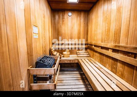 Sauna traditionnel en bois avec bancs, pierres chauffantes et seau d'eau. Banque D'Images