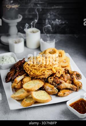 Rondelles d'oignon doré et sauces fumées servies sur assiette blanche Banque D'Images