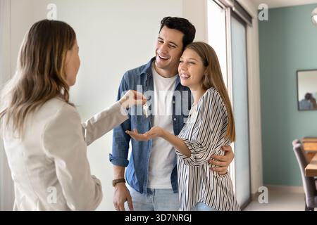 Jeune couple de jeunes mariés reçoit les clés de l'agent immobilier Banque D'Images