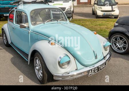 Vintage bleu clair et blanc Volkswagen Beetle garé sur le trottoir à côté d'autres véhicules par une journée ensoleillée lors d'un événement de rassemblement de voitures Banque D'Images