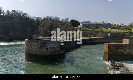 Vue aérienne du port en pierre accidenté embrassant les eaux turquoises tranquilles sous les falaises verdoyantes, Charlestown, Saint Austell, Royaume-Uni. Banque D'Images