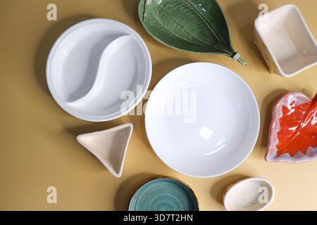 Composition avec des plaques et des bols en céramique propres et colorés sur fond jaune Banque D'Images