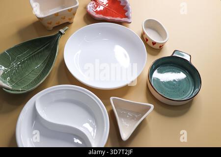 Composition avec des plaques et des bols en céramique propres et colorés sur fond jaune Banque D'Images