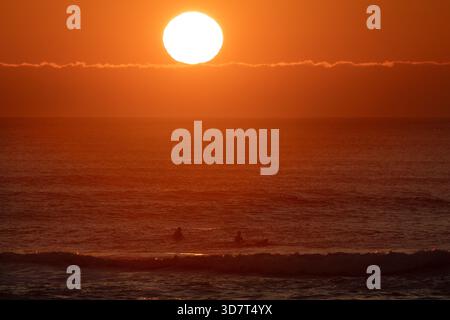 Surfeurs dans l'eau au coucher du soleil sur Ocean Beach à San Francisco Banque D'Images