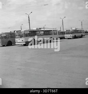 Slavyansk, Ukraine, URSS - 1983 : une flotte de trolleybus soviétiques ZiU-9 est garée en diagonale dans le terrain extérieur du dépôt de l'administration des trolleybus de la ville. Les véhicules électriques s'alignent sur la vaste surface asphaltée sous le réseau complexe de fils de contact aérien. De grands lampadaires en béton se tiennent en arrière-plan. Cette photo d'archives en noir et blanc capture l'échelle du système de transport public, de la logistique de la flotte et de l'atmosphère industrielle de la paisible ville du Donbass. Banque D'Images