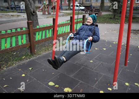 Heureuse femme âgée de 90 ans active ayant du plaisir sur une balançoire dans le parc à l'extérieur Banque D'Images