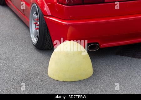 Hémisphère jaune restrictif sur la route asphaltée dans l'aire de stationnement et il y a une voiture garée inconnue devant elle. La voiture a heurté une sphère de béton Banque D'Images