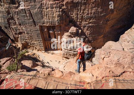 Touriste debout sur le bord de falaise surplombant le Trésor à Petra, Jordanie Banque D'Images