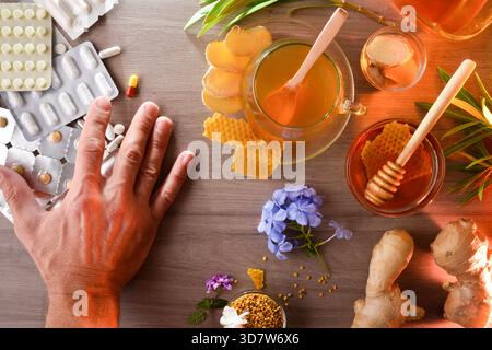Mains séparant les blisters avec des pilules et des capsules pour le traitement médical sur une table en bois avec une infusion de produits alternatifs naturels pendant une h. Banque D'Images