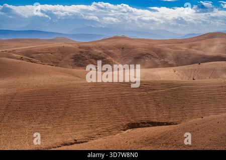Vaste paysage désertique avec des dunes de sable ondulantes sous un ciel bleu vif avec des nuages éparpillés. Désert d'Agafay, Marrakech-Safi, Maroc Banque D'Images