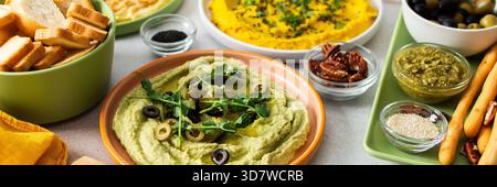 Une planche de charcuterie vibrante présente du brocoli, du curcuma, du houmous classique et de la betterave, associés à des olives, craquelins, et garnitures fraîches, parfait pour Banque D'Images