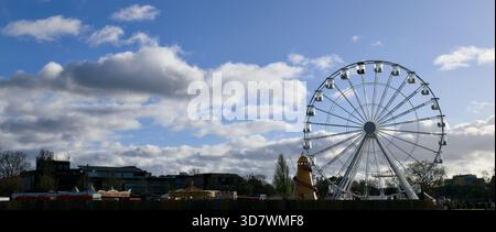 Grande grande roue installée dans une zone de parc verdoyante pour un marché de Noël festif. Banque D'Images
