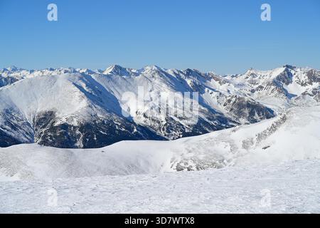 Panoramic view from the extensive Lachtal winter landscape to the snow-covered Greim mountain range under bright blue sky. Banque D'Images