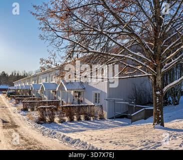 Maisons scandinaves enneigées idylliques sous la lumière chaude du soleil d'hiver Banque D'Images