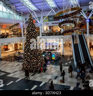 Un immense sapin de Noël décoré se dresse dans l'atrium du Liffey Valley Shopping Centre, Dublin. Entouré de lumières, il capture le HOL du centre commercial irlandais Banque D'Images