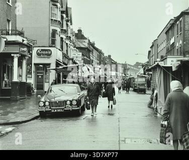 Vue générale de High Street, Walthamstow, le plus long marché de rue d'Europe, Londres, 1972. Pris de l'extérieur de la maison publique Chequers. Voiture Jaguar garée. Rossi's de Londres au numéro 145a. Étals de marché, acheteurs et piétons. Banque D'Images