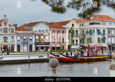 Aveiro, Portugal - 14 juin 2025 : les bateaux Moliceiros sont amarrés le long du canal Aveiro, présentant une architecture vibrante et une atmosphère urbaine animée Banque D'Images