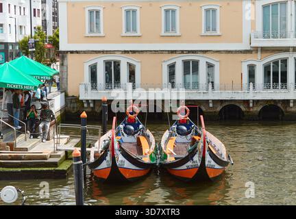 Aveiro, Portugal - 14 juin 2025 : les bateaux Moliceiros sont amarrés le long du canal Aveiro, présentant une architecture colorée et une ambiance animée pour les touristes Banque D'Images