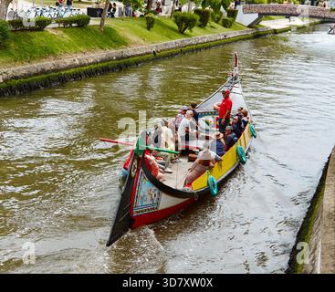 Aveiro, Portugal - 14 juin 2025 : un bateau traditionnel moliceiros rempli de touristes glisse à travers le canal pittoresque d'Aveiro, mettant en valeur le col vibrant Banque D'Images