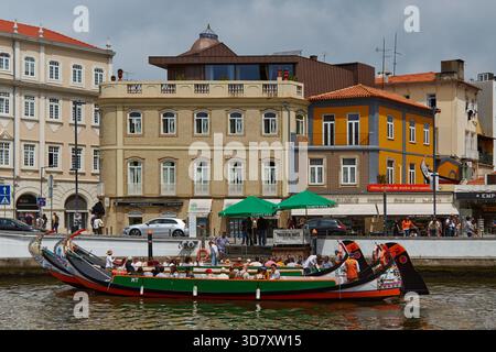 Aveiro, Portugal - 14 juin 2025 : les bateaux Moliceiros sont amarrés le long du canal Aveiro, mettant en valeur des bâtiments colorés et une scène urbaine dynamique au Portugal Banque D'Images