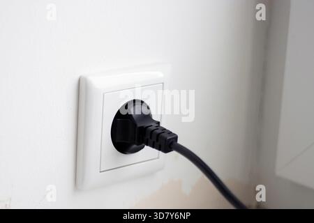 Gros plan du câble noir branché dans la prise Banque D'Images