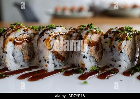 Rouleaux de sushi recouverts de sauce et de ciboulette, créant un plat japonais appétissant Banque D'Images