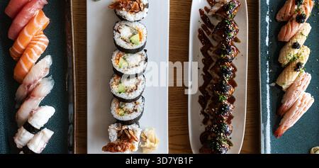 Variété de sushi japonais, nigiri et rouleaux de maki disposés sur des assiettes de service Banque D'Images