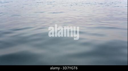 Surface calme de l'eau de mer après le coucher du soleil, seulement de petites vagues - fond marin abstrait Banque D'Images