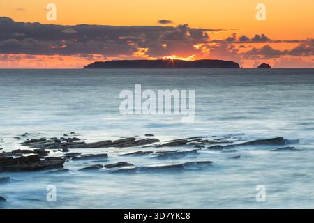 Coucher de soleil sur les îles Berlengas, lumière dorée sur les falaises rocheuses et la mer turquoise, grottes marines et îlots silhouettés sur un ciel chaud. Humeur tranquille. Banque D'Images
